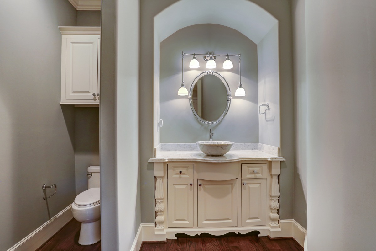 Beautiful powder bathroom with furniture-like cabinetry and a carrara marble vessel sink