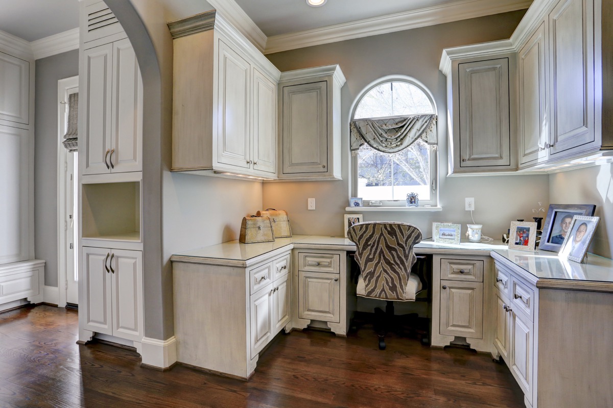Command center is adjacent to mudroom and has furniture-like built-in cabinetry painted with a subtle antiqued finish
