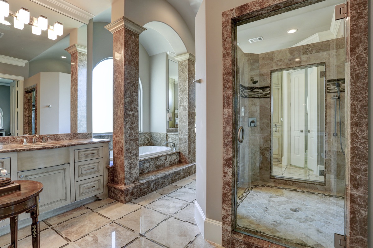 Grand master bathroom with dark Emperador marble and inlaid accents in flooring and shower