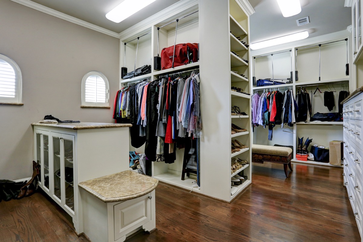 Master closet offers pull-downs for extra storage, and features marble-topped islands, benches, and chests