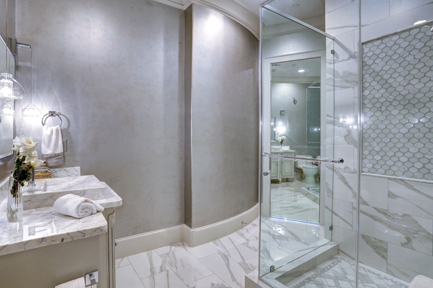 Gently curving wall, white Carrara marble sink and inlaid tile shower